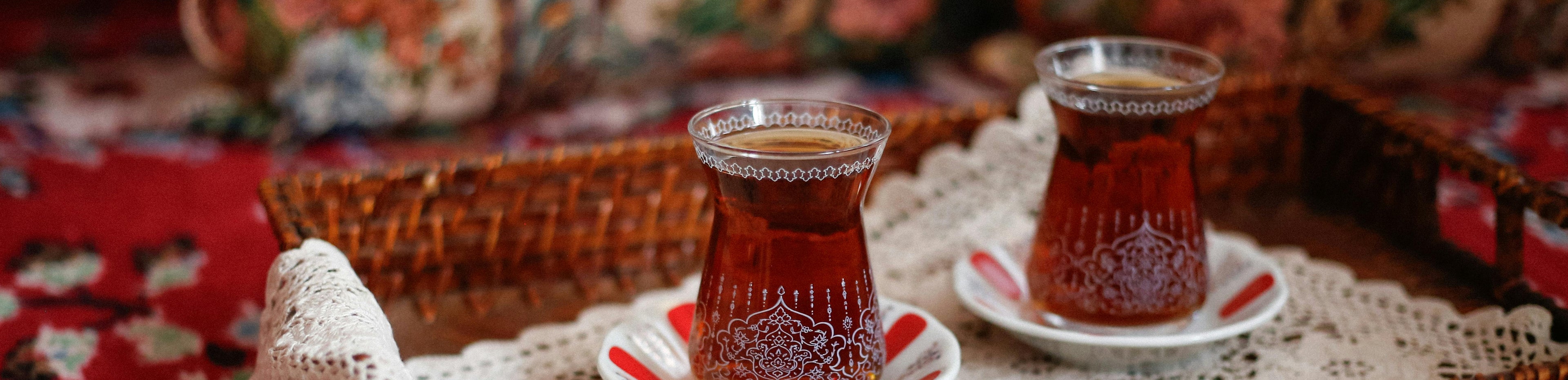 Two glasses of tea on a woven tray with a decorative background